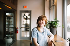 Lady, smiling, sitting at a bar in a cafe or museum