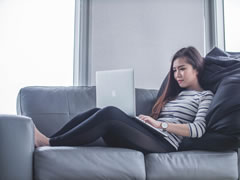 Lady, reclining on sofa using laptop